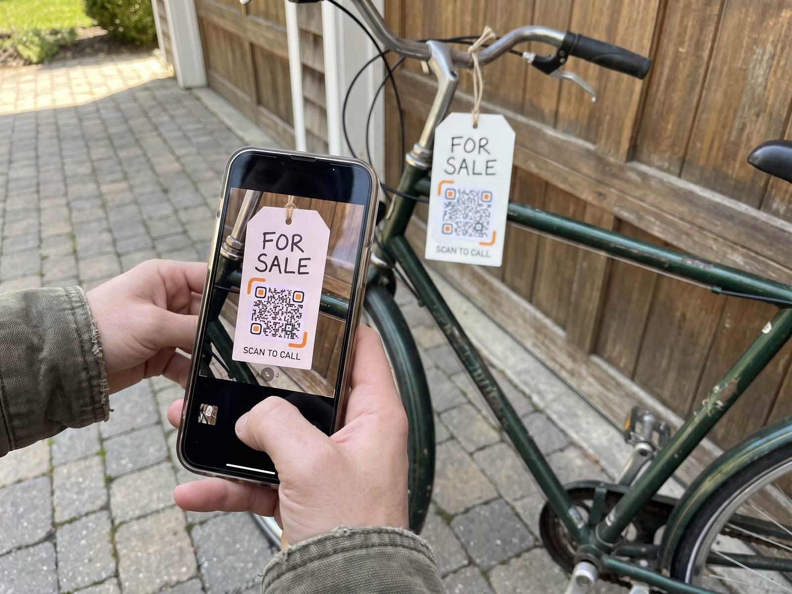 A phone scans the “For sale · Scan to call” tag hanging from a used bicycle.