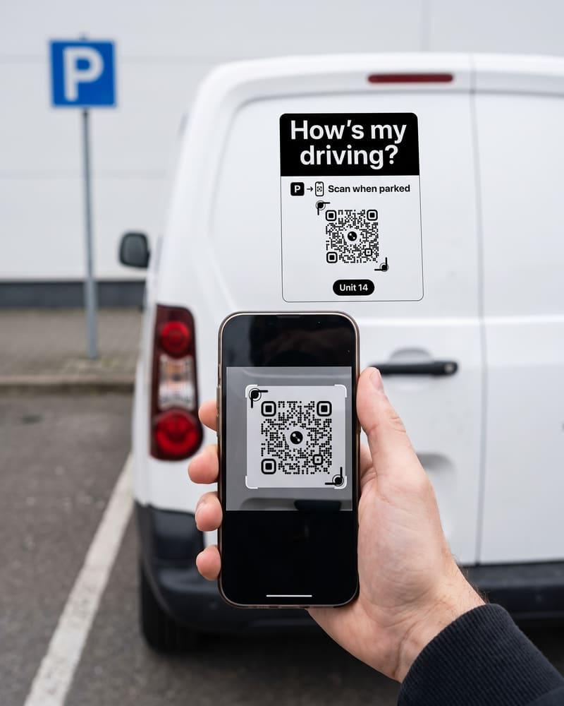 A hand holds a phone up to the sign on a parked van, a blue parking sign behind it.