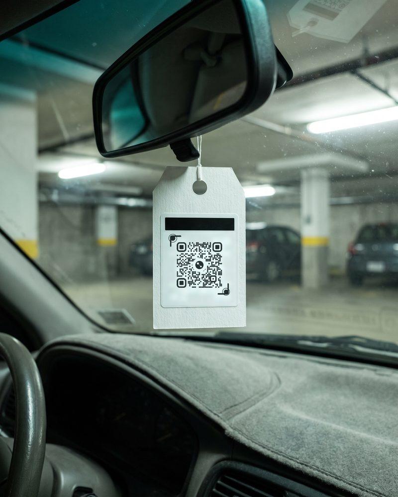 A QR hang tag on the rear-view mirror in an underground parkade