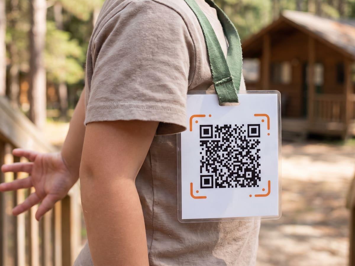 A child at a summer camp wearing an iQR code card on a green lanyard.